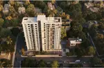 An aerial view of Primarc Aahana showcasing a modern high-rise residential tower with a clean white facade, surrounded by lush greenery and low-rise neighborhood buildings. The project is set along a well-planned road network with landscaped surroundings, offering a peaceful and well-connected urban living environment.